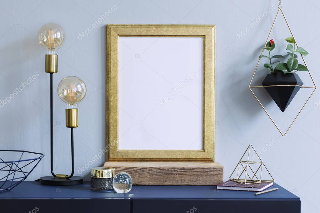 Interior floral poster mock up with vertical wooden frame, table lamp, gold pyramid, accessories and hanging plants in geometric pot on the grey wall background. Concept with navy blue shelf.