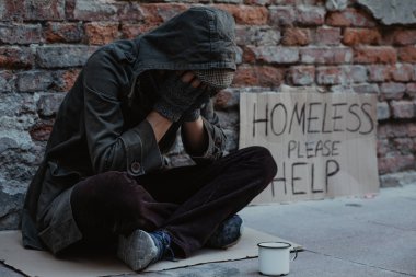 Evsiz adam kaldırımda oturan ve dinleyici notları için soran