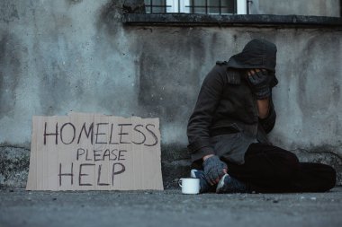 Homeless man sitting on pavement and asking for handouts clipart