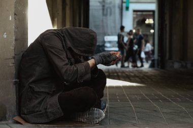 Evsiz adam kaldırımda oturan ve dinleyici notları için soran