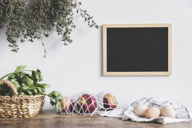 Dize-çanta, yumurta ve ahşap mutfak masasında yeşil yaprakları kırmızı elmalar