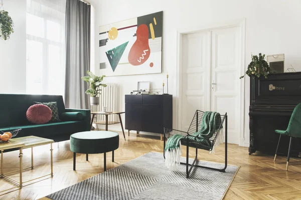 Stylish living room with green velvet sofa, black vintage piano and abstract art on wall