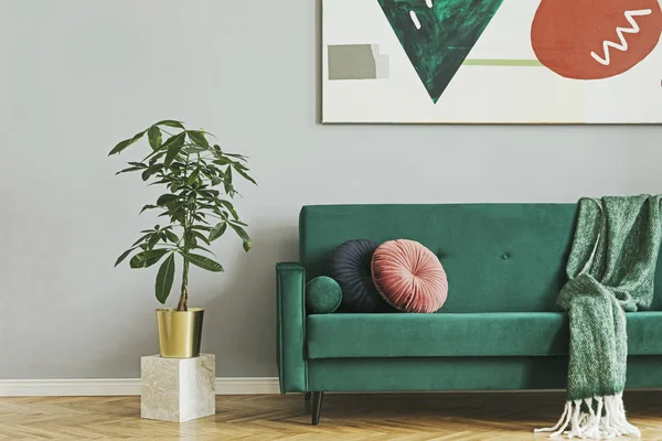 Stylish living room with green velvet sofa and abstract art on wall