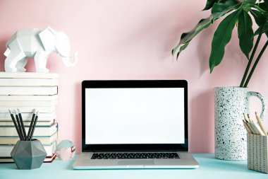Dizüstü bilgisayar ekranı ve ofis aksesuarları pastel pembe arka plan üzerinde yukarı sahte ile modern çalışma alanı 