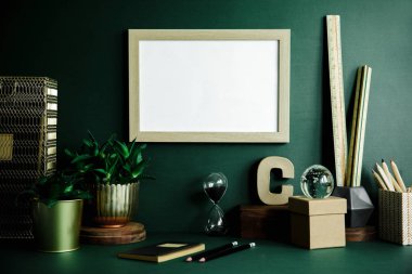 Sahte kadar poster çerçevesi, seramik şekil, bitkiler üzerinde yeşil arka plan ile yaratıcı dolap