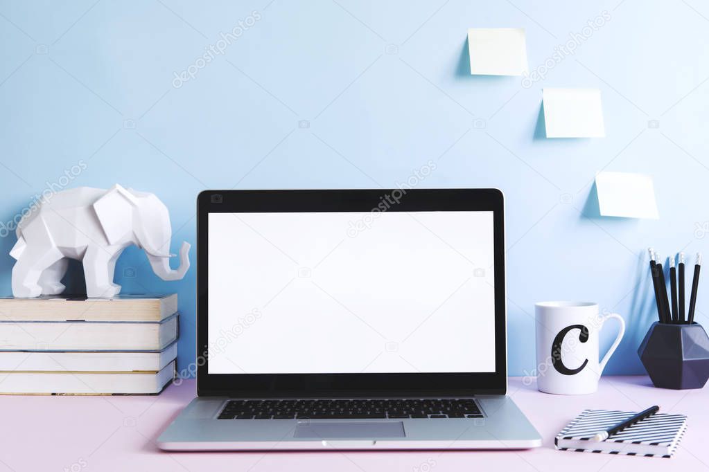 Modern work-space with laptop mock up screen and office accessories on pastel blue background 