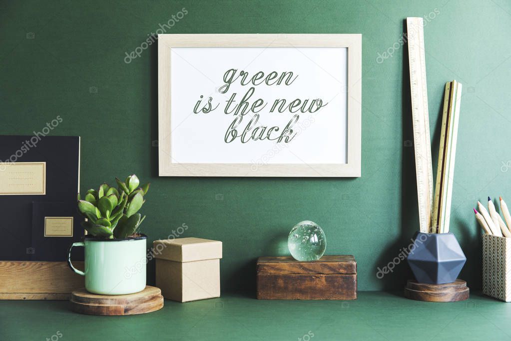 Creative cupboard with mock up poster frame, ceramic figure, plants on green background