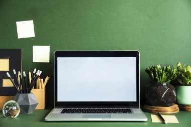 Dizüstü bilgisayar ekranı ve ofis aksesuarları yeşil zemin üzerine kadar sahte ile modern çalışma alanı 