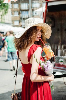 Soğuk suyu ihale çiçek buketi elinde fincan ile hasır şapkalı kadın kıvırcık 