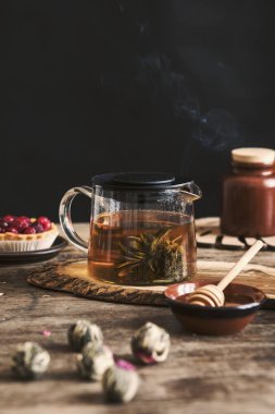 Chrysanthemum çayı ile tarçın kabukları ve ahşap zemin üzerine bal ile fincan tabağı ile cam çaydanlık