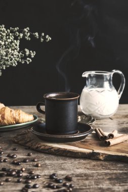 Bir fincan kahve, süt ve kek ile mutfak iç vintage ve şık kompozisyon. Sabah kahvaltısı kış ve sonbahar konsepti. Siyah arka plan.