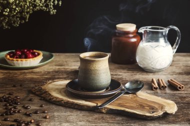 Tarçın kabukları ve berry tart, kavanoz arka plan üzerinde süt ile ahşap Pano rustik kil Kupası 