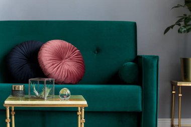 Yeşil kadife tasarım kanepe, yastık, altın sehpa ve aksesuarları üzerinde hava bitkileri ile lüks ev iç. . Gri duvarlar ve kahverengi ahşap parke. Modern oturma odası konsepti.