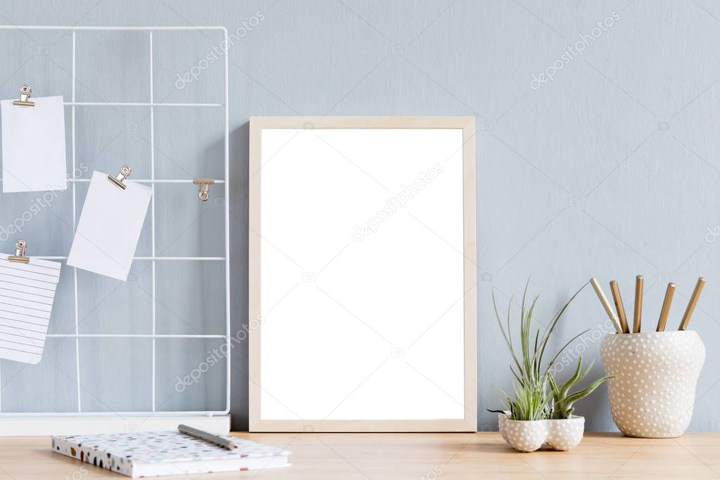 Modern workplace with blank frame on wooden table 