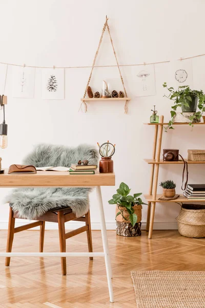 Stylish scandinavian home interior of open space, with a lot of plants, design accessories, bamboo shelf, wooden desk and hanging mock up forest drawings . Botany concept of home decor. Sunny room.