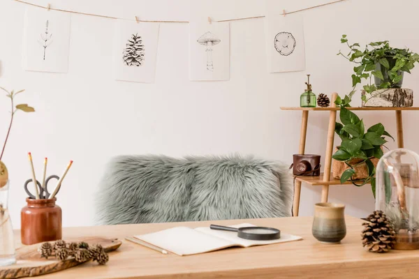 Stylish scandinavian home interior of open space, with a lot of plants, design accessories, bamboo shelf, wooden desk and hanging mock up forest drawings . Botany concept of home decor. Sunny room.