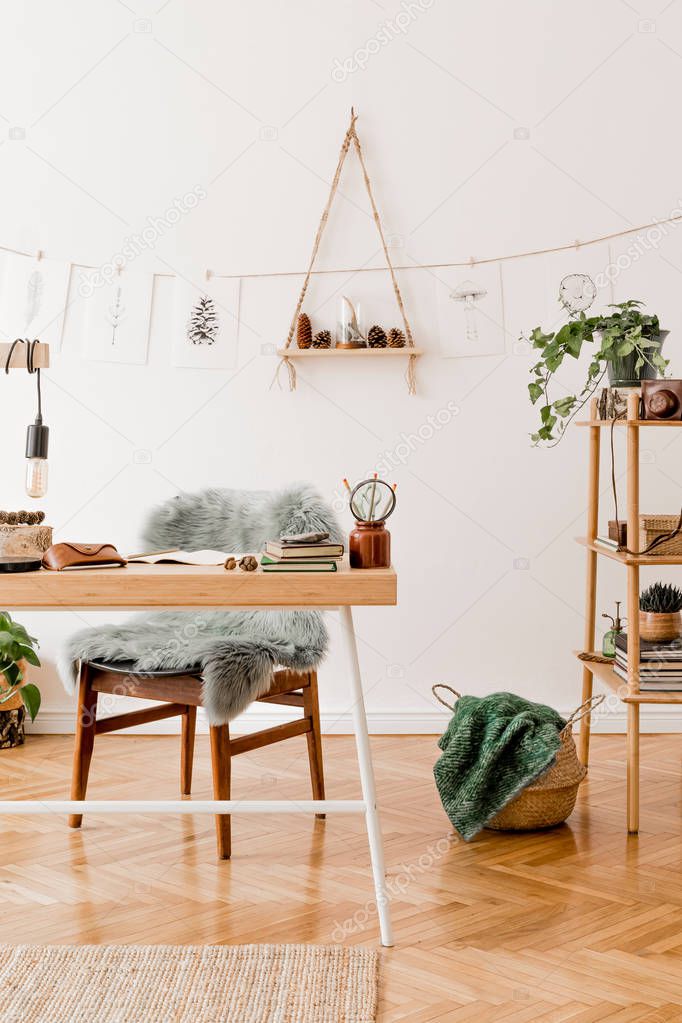 Stylish scandinavian home interior of open space, with a lot of plants, design accessories, bamboo shelf, wooden desk and hanging mock up forest drawings . Botany concept of home decor. Sunny room.
