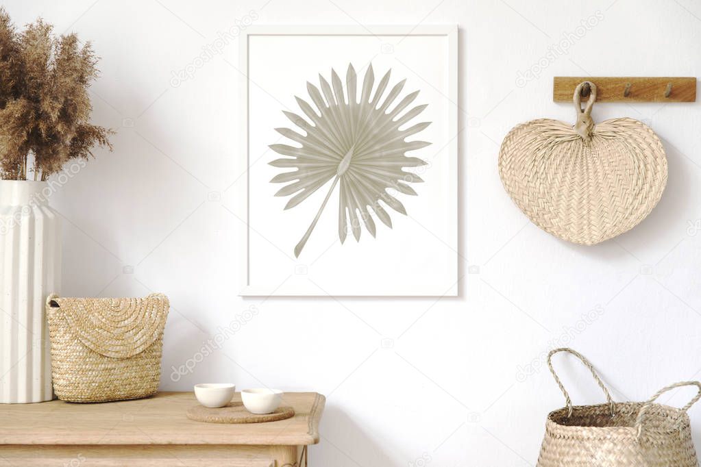 Stylish korean interior of living room with brown mock up poster frame, elegant accessories, flowers, wooden shelf and hanging rattan leaf. Minimalistic concept of home decor. Template. Real photo.