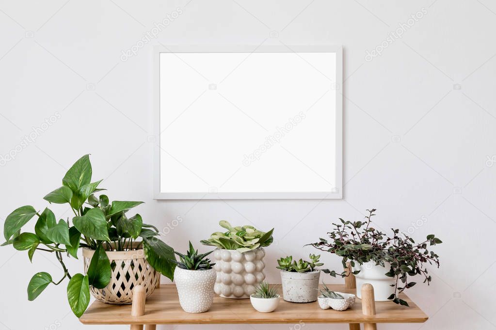 Stylish scandinavian interior with mock up poster frame, design bamboo commode and beautiful composition of plants in different hipster pots. Modern home decor. Minimalistic concept. Home garden.