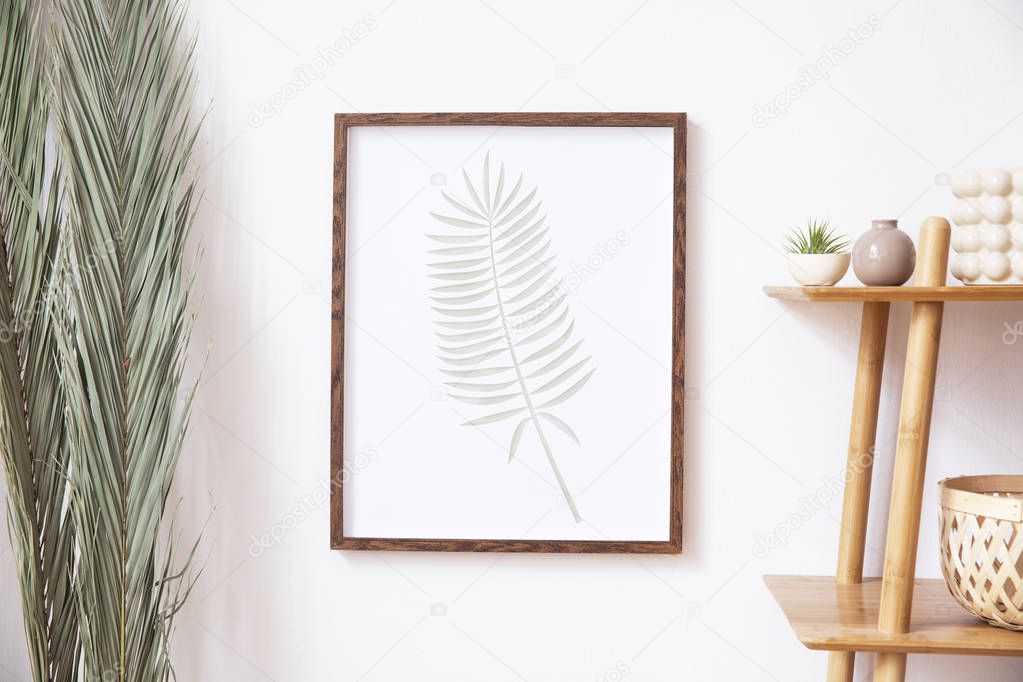 Stylish korean interior of living room with white mock up poster frame, elegant accessories, wooden shelf and tropical palm leafs. Minimalistic concept of home decor. Template. Bright room.