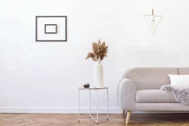 Tasarım gri kanepe, geometrik lamba, sehpa, çiçekler, battaniye ve zarif aksesuarlar ile şık minimalist oturma odası Beyaz duvarlara poster çerçevesi mock. Minimalistic ev dekor. 