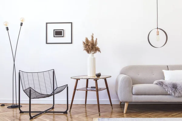 Stylish minimalistic living room with design grey sofa, black armchair, geometric lamp, retro table and elegant accessories Mock up posters frame on the white walls. Minimalistic home decor.