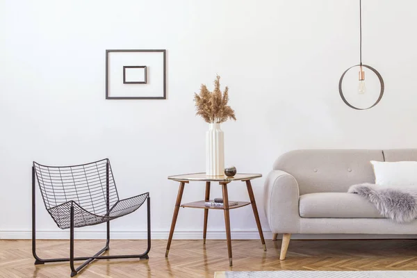 Stylish minimalistic living room with design grey sofa, black armchair, geometric lamp, retro table and elegant accessories Mock up posters frame on the white walls. Minimalistic home decor.