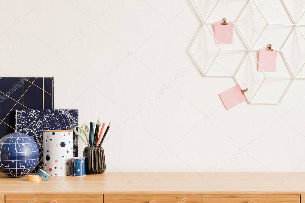 Cosmic and modern home interior with wooden desk, cool office accessories, tapes, supplies, notes, memo sticks, pencils. Scandinavian home decor. Minimalistic concept. Template. Copy spce.