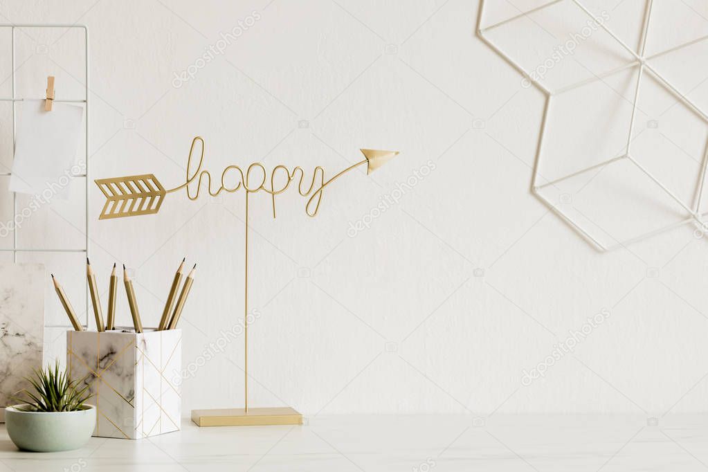White and stylish home interior with cool office accessories, notes, memo sticks, pencils and air plant. Gold happy sign. Scandinavian home decor. Minimalistic concept. Template. Copy space.