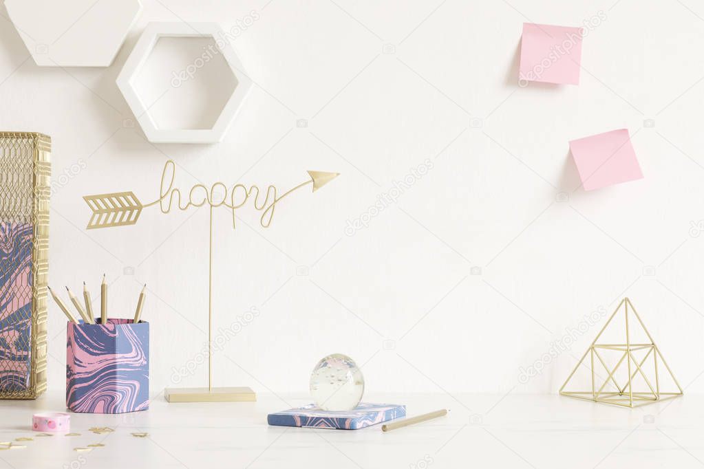 Cosmic and modern home interior with cool office accessories, tapes, supplies, notes, memo sticks, pencils. Gold happy sign and pyramid. Stylish home decor. Minimalistic concept. Template. Copy spce.