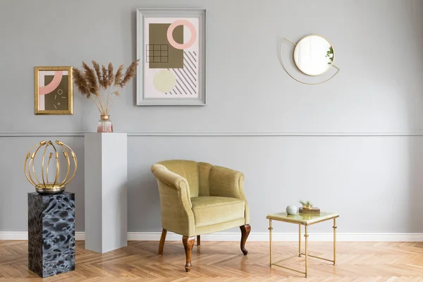 Stylish and luxury living room of apartment interior with elegant green armchair, retro table, marble stands, design lamps, chic accessories and gold mirror. Mock up frames on the molding gray wall.