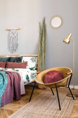 Tasarım mobilyalar, bal sarı koltuk, duvarlarda gri makrame ve zarif aksesuarlar ile yatak odası şık ve lüks iç. Güzel çarşaflar, battaniyeler ve yastıklar. Sıcak ev dekorasyonu.