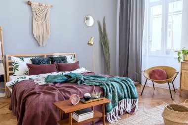 Tasarım mobilyalar, gri makrame, altın lamba, zarif aksesuarlar ve kitaplar ile gece masası ile yatak odası şık ve lüks iç. Güzel çarşaflar, battaniyeler ve yastıklar. Rahat ev dekorasyonu.