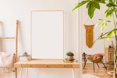 Poster çerçevesi, ahşap merdiven, altın koltuk, tasarım aksesuarları ve mobilyalar, bitkiler ve sarı makrame kadar sahte daire Güneşli scanidnavian iç. Odaların şık ev dekorasyonu. Gerçek fotoğraf