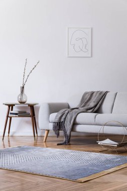 Tasarım gri kanepe ve retro küçük masa ile ev alanı şık scandi iç. Tasarım aksesuarları ile oturma odası ve poster çerçevesi kadar mock. Zarif bir dekor. Modern halı ile kahverengi ahşap parke.