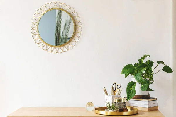 木製の机 デザイン金のアクセサリー 本や植物とスタイリッシュなスキャニドナビアのインテリア 白い壁に美しい鏡ホームインテリアのクリエイティブデスク 暖かくて日当たりの良いお部屋 スペースをコピーします 実際の写真 — ストック写真