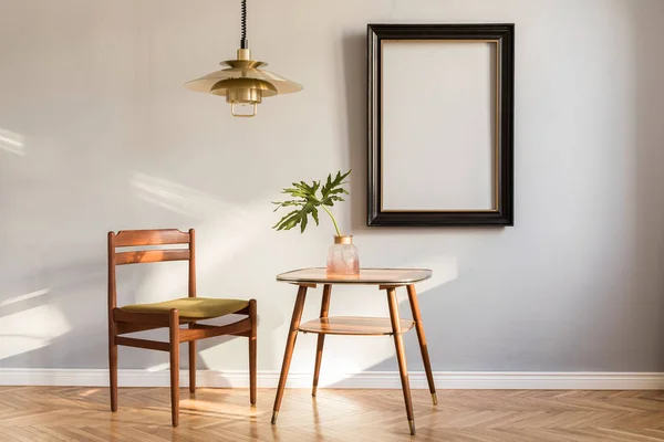デザインチェア ゴールドランプ トロピカルリーフ付きの小さなテーブル 日当たりの良いデザインのレトロなインテリア 灰色の背景壁に黒のモックアップフレーム リビングルームのミニマルな概念 実際の写真 — ストック写真