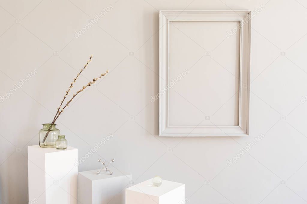 Minimalistic and design home decor with mock up grey poster frame and white pedestals with stylish accessories and flowers. Eclectic and modern room interior. Template. Blank. Real photo.