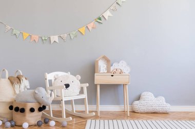 İskandinav çocuk odası, gri duvar, doğal sepet, çocuk sandalyesinde oyuncak ayı. Renkli bayrakları ve aksesuarları olan ahşap rafı olan sevimli modern bir iç mekan. Boşluğu kopyala.