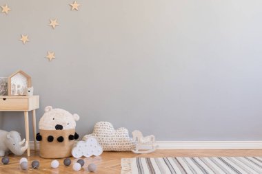 Oyuncaklar, çocuk sandalyesi, oyuncak ayı ve küçük raf ile doğal sepet ile şık İskandinav yenidoğan bebek odası. Gri arka plan duvarları, ahşap parke ve yıldız desenli modern iç mekan.