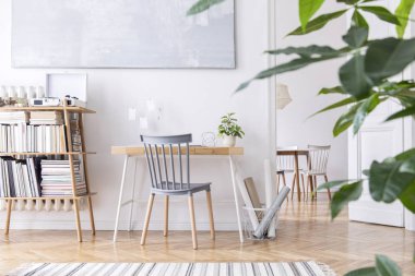 Yaratıcı ahşap masa, aksesuarları, kitaplar ve bitkiler ile bambu bookstand ile iç şık İskandinav ev dekorasyonu. Açık alan ve oturma odası. Kahverengi ahşap parke ve şık halı.