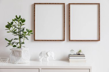 Kitap, şık pot, fil figürü ve ev aksesuarları güzel bitki ile iki kahverengi ahşap sahte fotoğraf çerçeveleri ile iç şık beyaz ev dekorasyonu. Minimalist İskandinav odası.