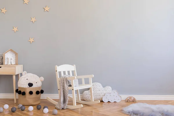 Oyuncaklar, çocuk sandalyesi, oyuncak ayı ve küçük raf ile doğal sepet ile şık İskandinav yenidoğan bebek odası. Gri arka plan duvarları, ahşap parke ve yıldız desenli modern iç mekan.