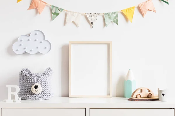 Oyuncaklar, oyuncak ayı, aksesuarları, bulut, renkli pamuk bayraklar ve doğal sepet ile şık İskandinav yenidoğan bebek odası. Fotoğraf veya poster çerçevesi kadar sahte modern iç. Gerçek fotoğraf. Şablon.