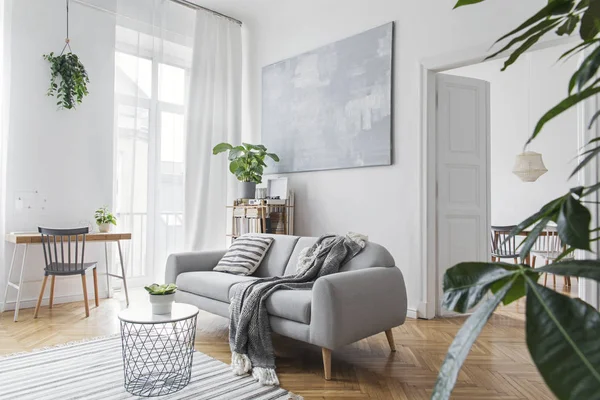时尚的斯堪的纳维亚客厅配有设计家具 竹书架和木制书桌 棕色木制镶木地板 白墙上的抽象绘画 不错的公寓明亮的客房现代装饰 — 图库照片