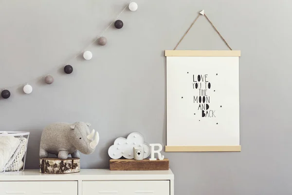 Stylish and cute scandinavian decor of child room with mock up poster, white shelf, natural toys, hanging cotton lamps, animal toy, basket for accessories and plush rhino. Bright and sunny interior.