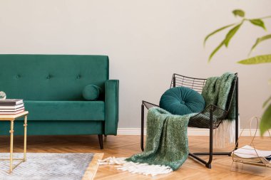 Minimalist ve şık ev iç tasarım yeşil kadife kanepe, bitkiler, tasarım mobilyalar, aksesuarlar, koltuk ve kolye lambası ile oturma odası dekor. Kahverengi ahşap parke ve gri duvarlar. 