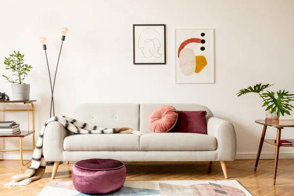 Tasarım kanepe, altın kitaplık, vintage masa ve beyaz duvarlarda posterler çerçeveleri kadar sahte oturma odası şık retro iç. Kahverengi ahşap parke, bitki ve yapraklı iç tasarım.