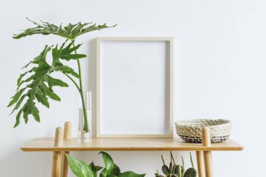 Güzel bitkiler, tropikal yapraklar ve aksesuarlar ile kahverengi bambu rafta fotoğraf çerçevesi kadar sahte İskandinav oda iç. Beyaz duvarlar. Rafların modern ve çiçek konsepti.