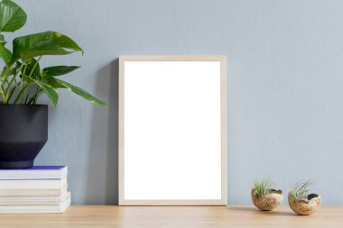 Tasarım hipster beyaz pot güzel bitki ile kahverengi ahşap masa üzerinde fotoğraf çerçevesi kadar sahte minimalist oda iç. Gri duvarlar. Poster çerçevesi kadar mock şık ve çiçek kavramı. 